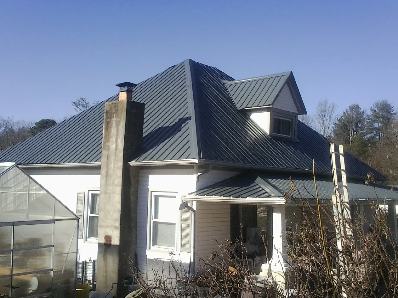 Dark blue standing seam metal roof on a white farmhouse with dormer — Slate & Tile Roof Repair by Roofing Brothers in Blandford