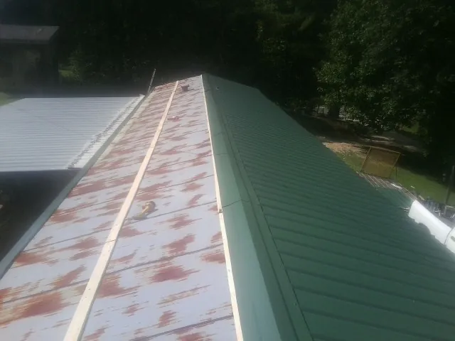 Old rusted panels beside newly installed green metal roofing — Wind Damage Roof Repair by Roofing Brothers in Blandford