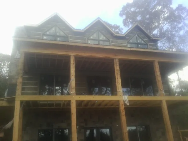 Dormers and porch framing on a large log home under construction — Roof Coating work by our crew in Blandford
