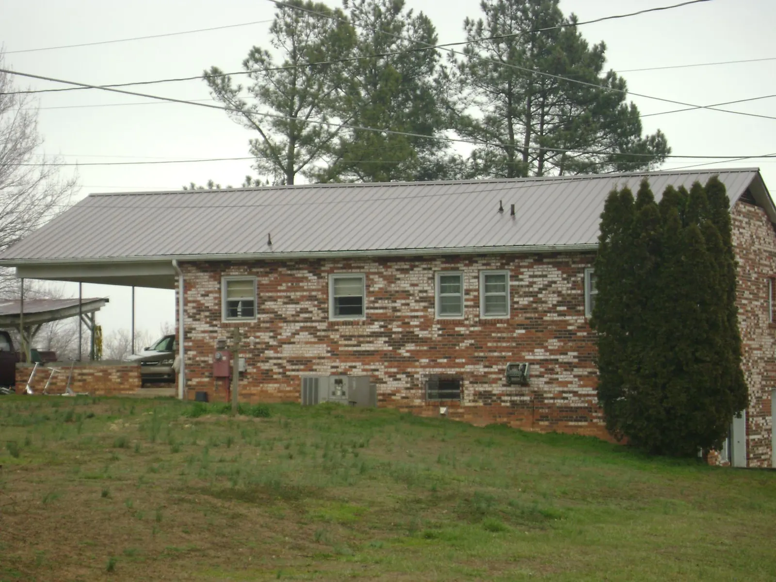 Gray metal roof on a brick split level home with a carport in Blandford