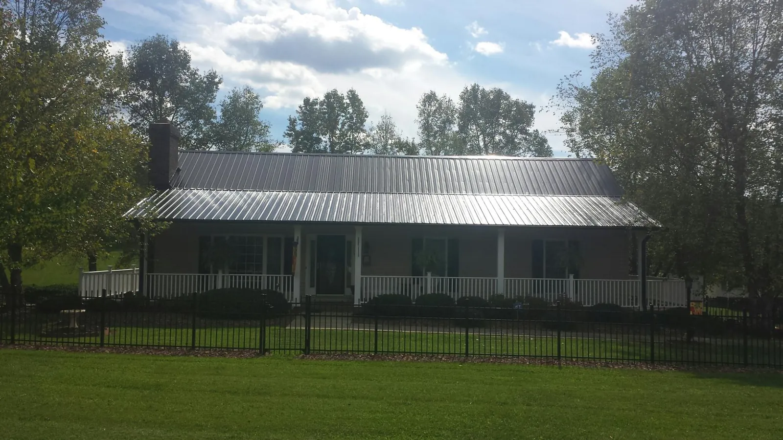 Gray metal roof on a brick ranch with a full width front porch — Gutter Guard Installation work by our crew in Blandford