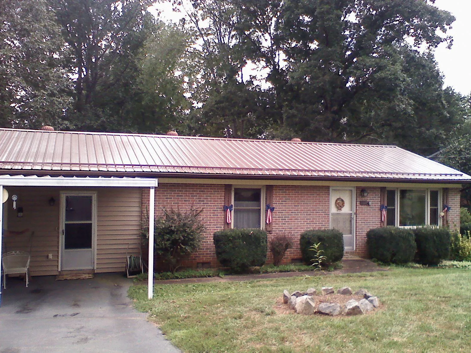 Bronze metal roof and carport on a brick ranch home — Roof Repair work by our crew in Blandford