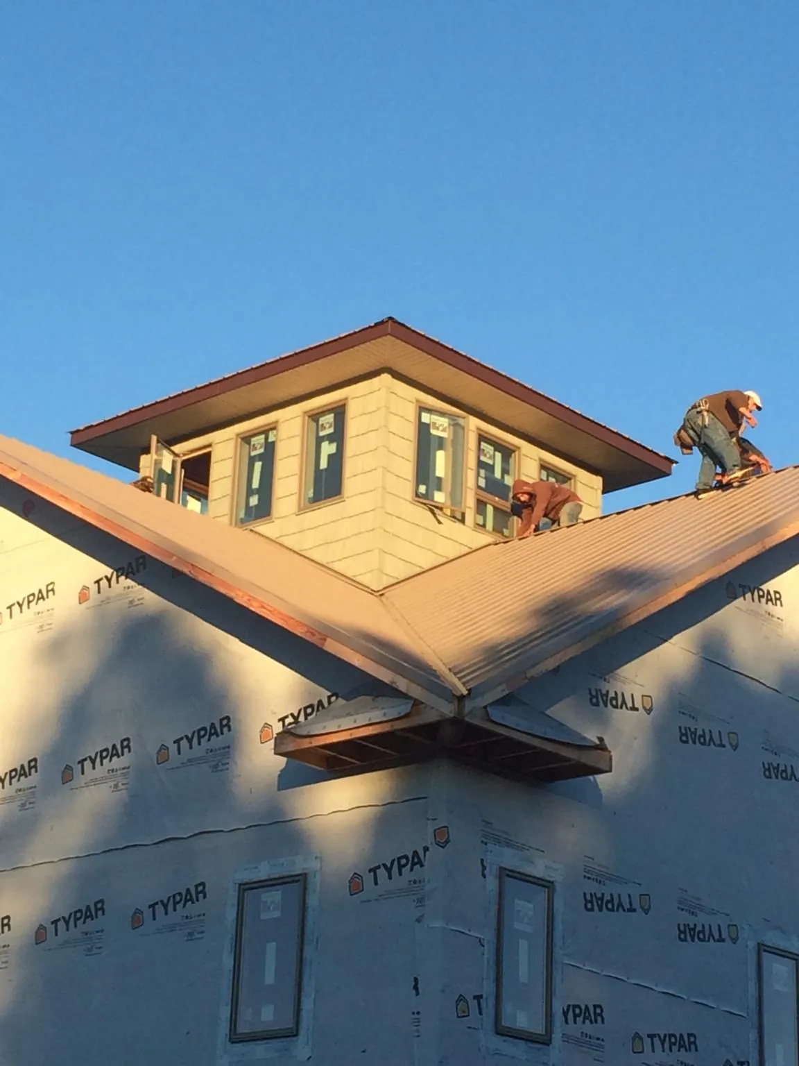 Roofers working around a rooftop cupola on a new metal roof at sunset — Roof Waterproofing in Blandford by Roofing Brothers